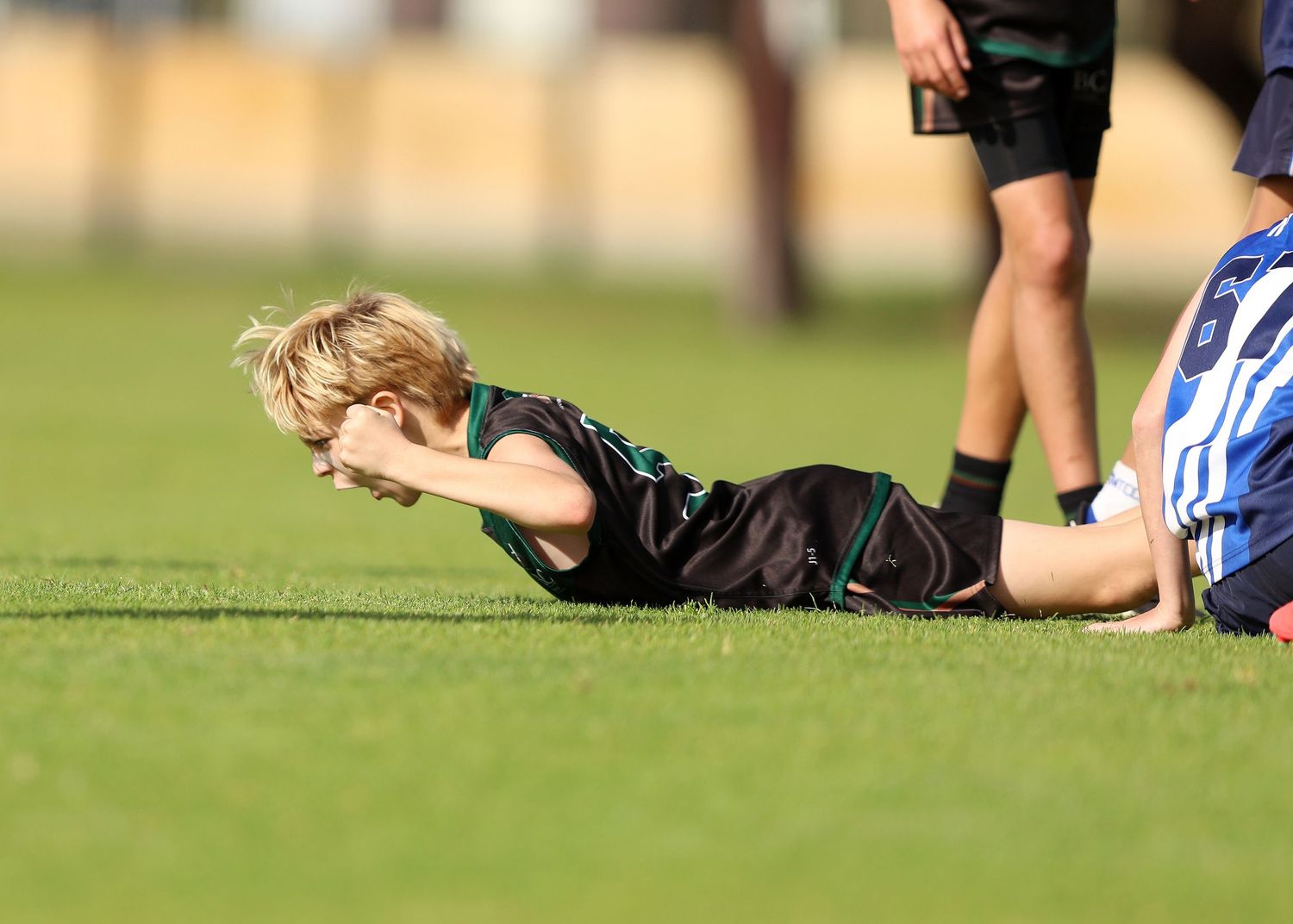 Rugby player makes a low tackle on opposing player during an intense match on grass field.