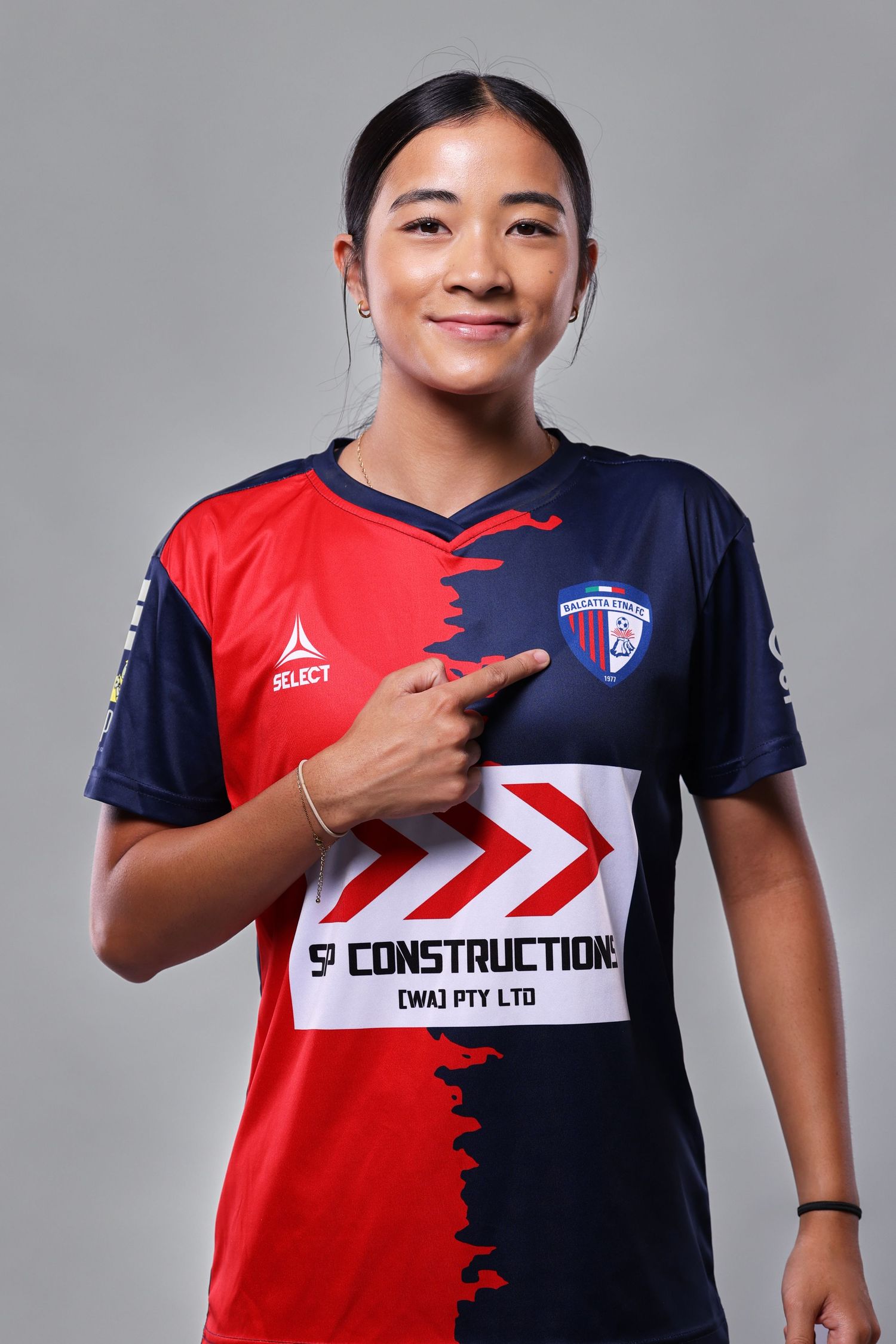 Athletic jersey design showing split red and navy blue color blocking with sponsor logo and team branding details.