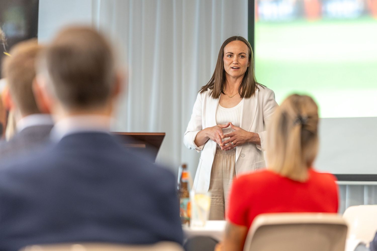 Business presenter speaking to audience in conference room setting.