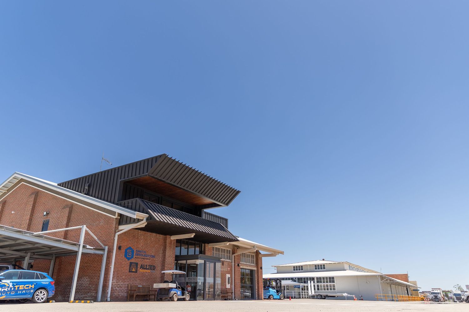 Modern brick building with dramatic angular roof overhangs and glass facade under clear blue sky at a transit station.