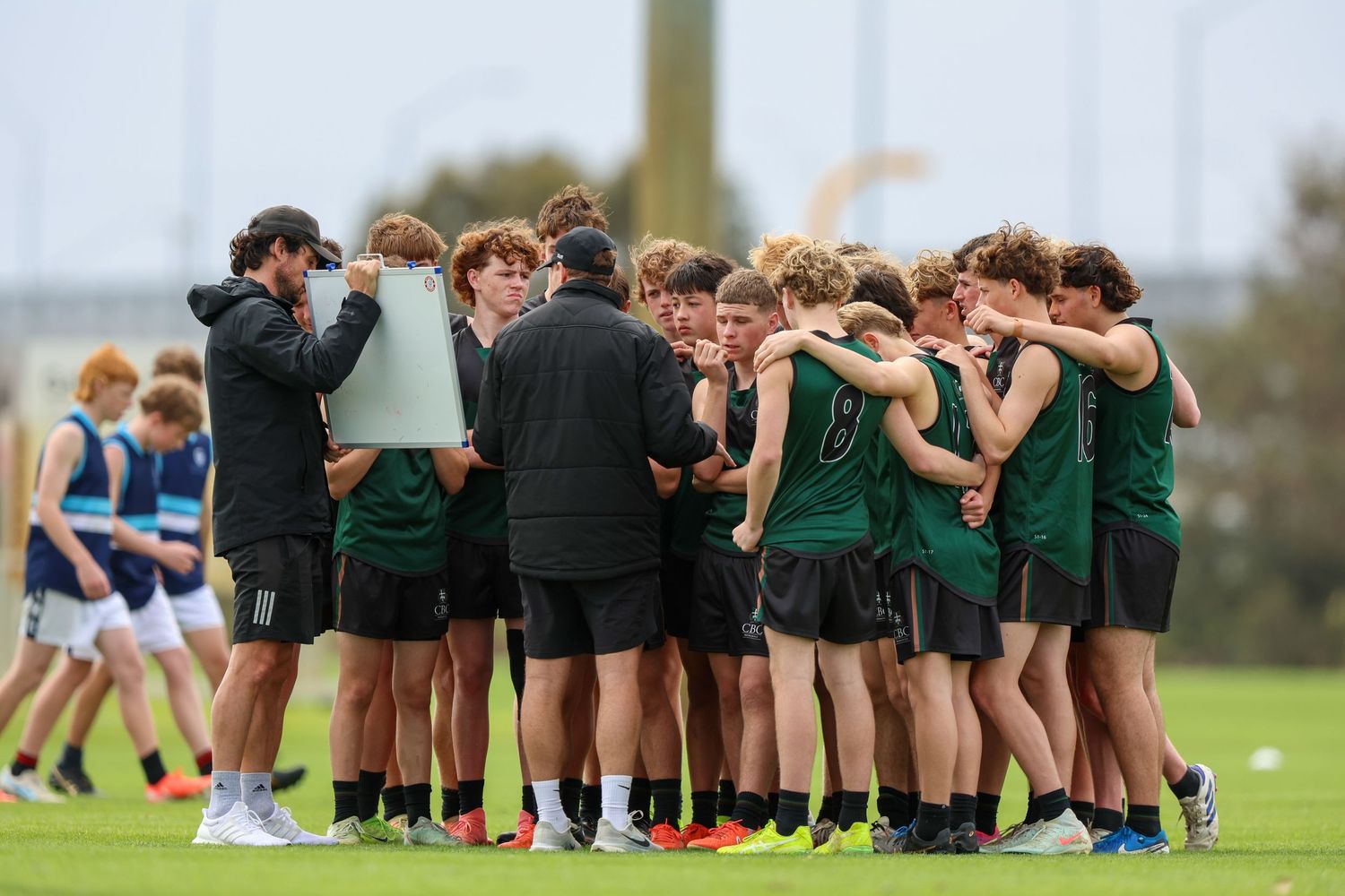 Sports team huddling together in a circle formation on an outdoor field during practice or pre-game ritual.