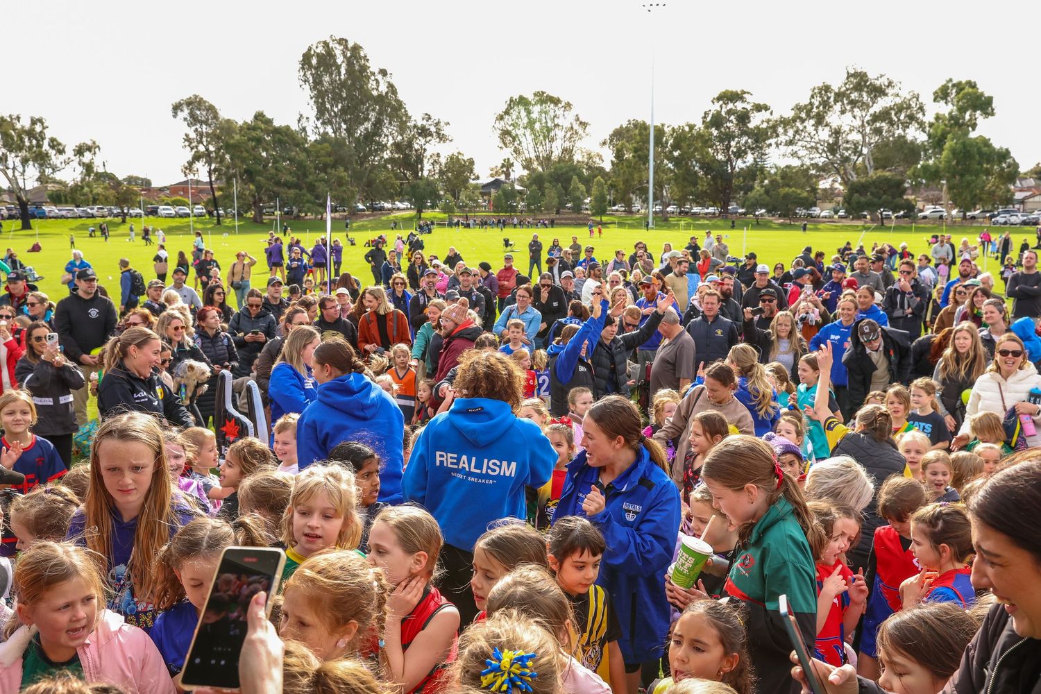 Crowd of students in colorful shirts gathered outdoors on a sunny day during a school event.