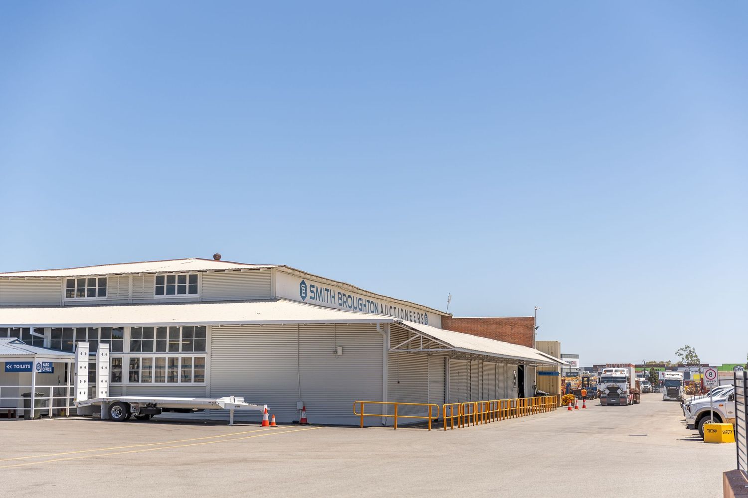 White industrial warehouse building with loading docks under clear blue sky at commercial distribution center.