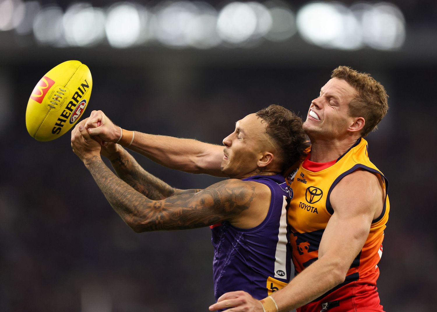 Two players contest for the ball during intense AFL match action.
