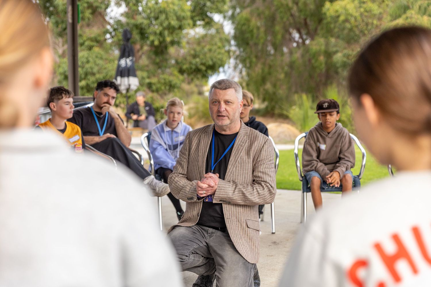 People seated outdoors listening to a speaker during a presentation event.