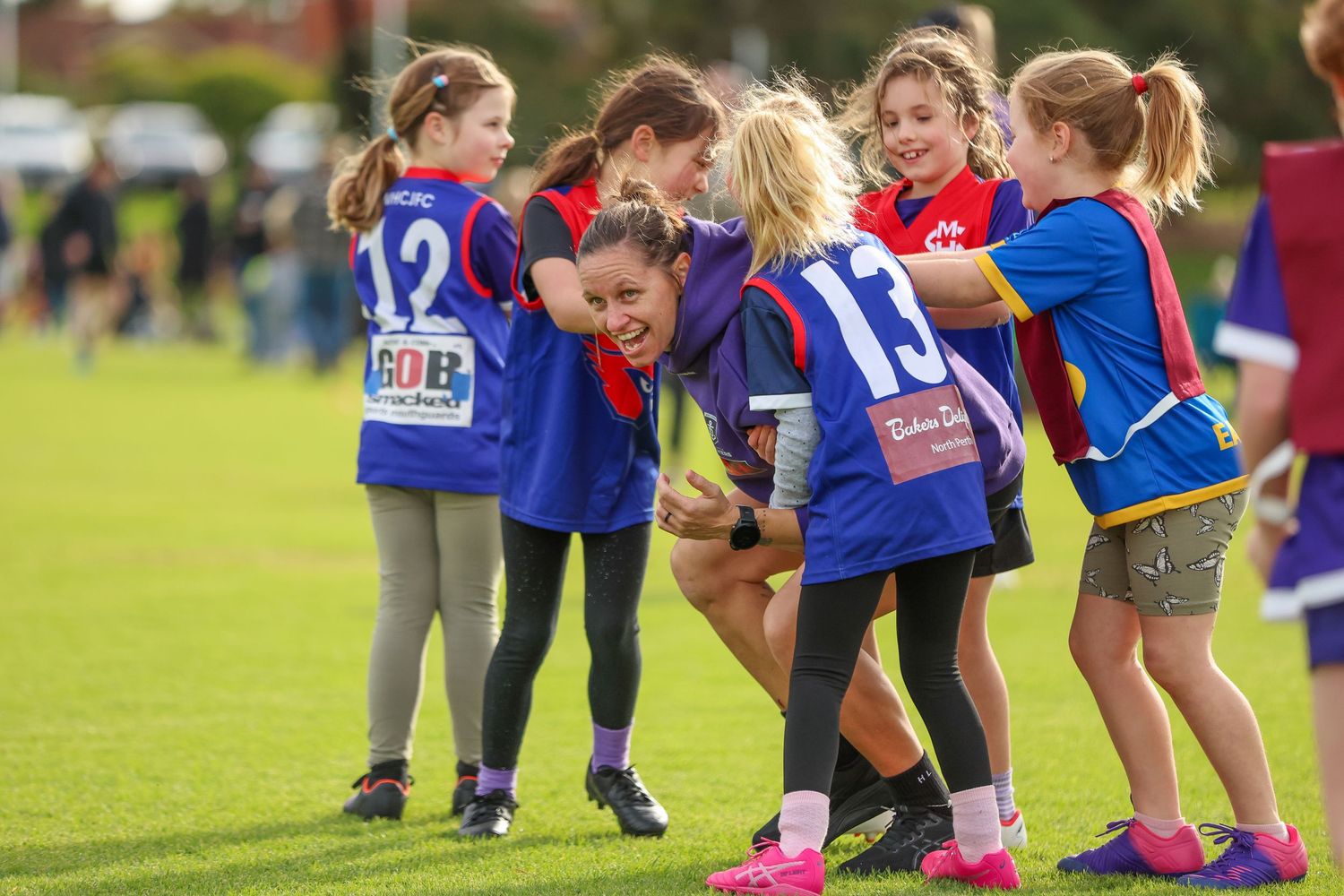 Young athletes in blue jerseys huddle together on a sports field during a youth sports event.