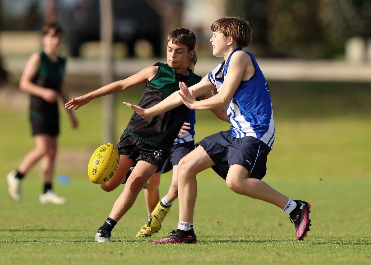 Two Australian Rules Football players battle for possession of the ball during a competitive match.