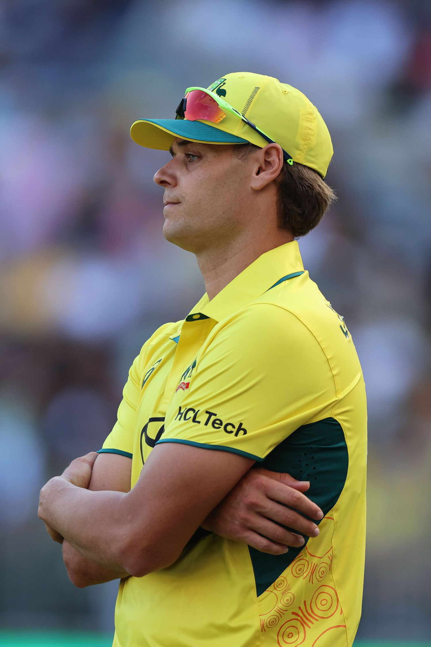 Cricket players in bright yellow uniforms look on intently during a match.