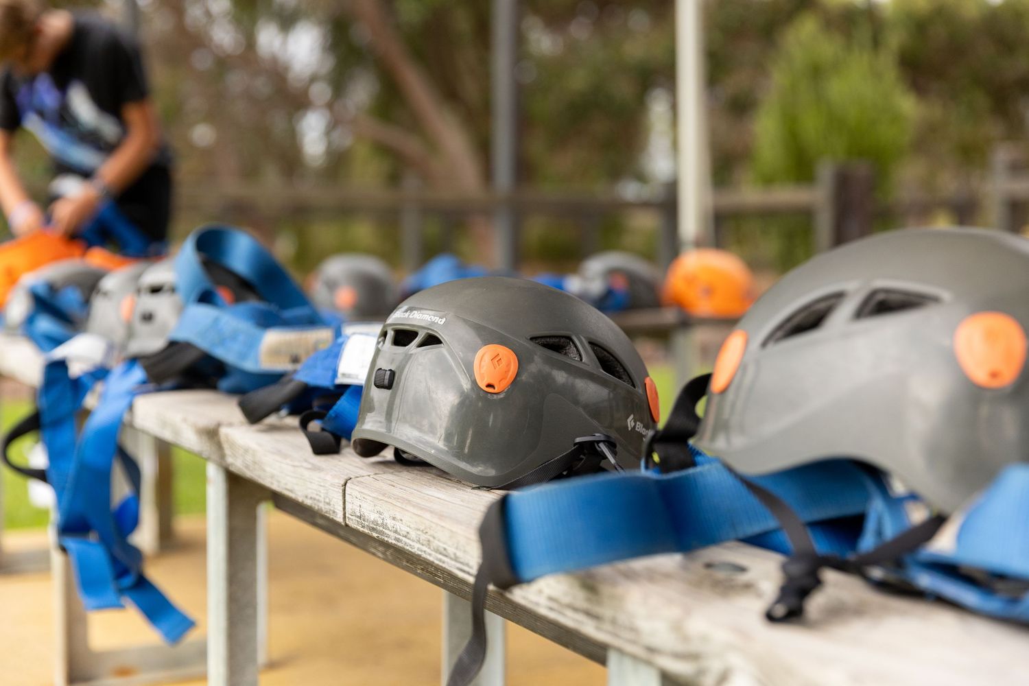 Row of gray and blue safety helmets lined up on outdoor equipment table.