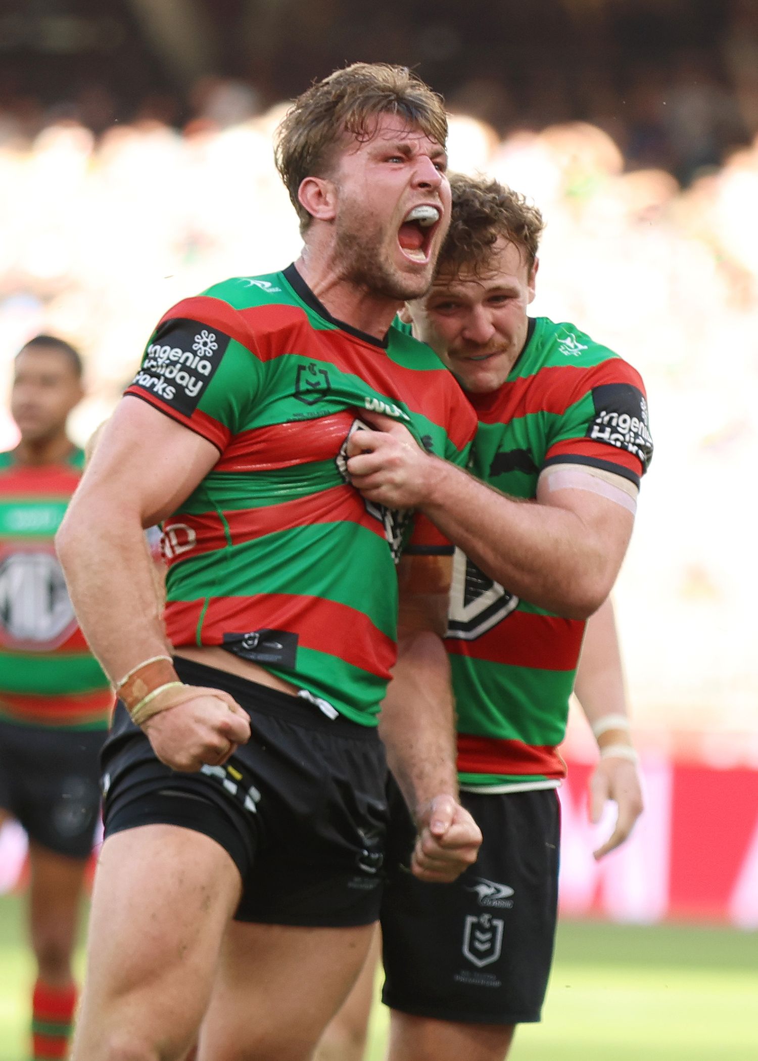 Rugby players in green and red striped jerseys celebrate emotionally during a match.