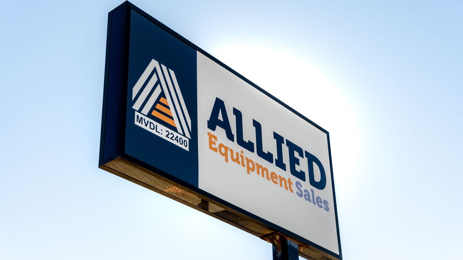 Illuminated Allied Equipment sign mounted on a pole against blue sky during daytime.