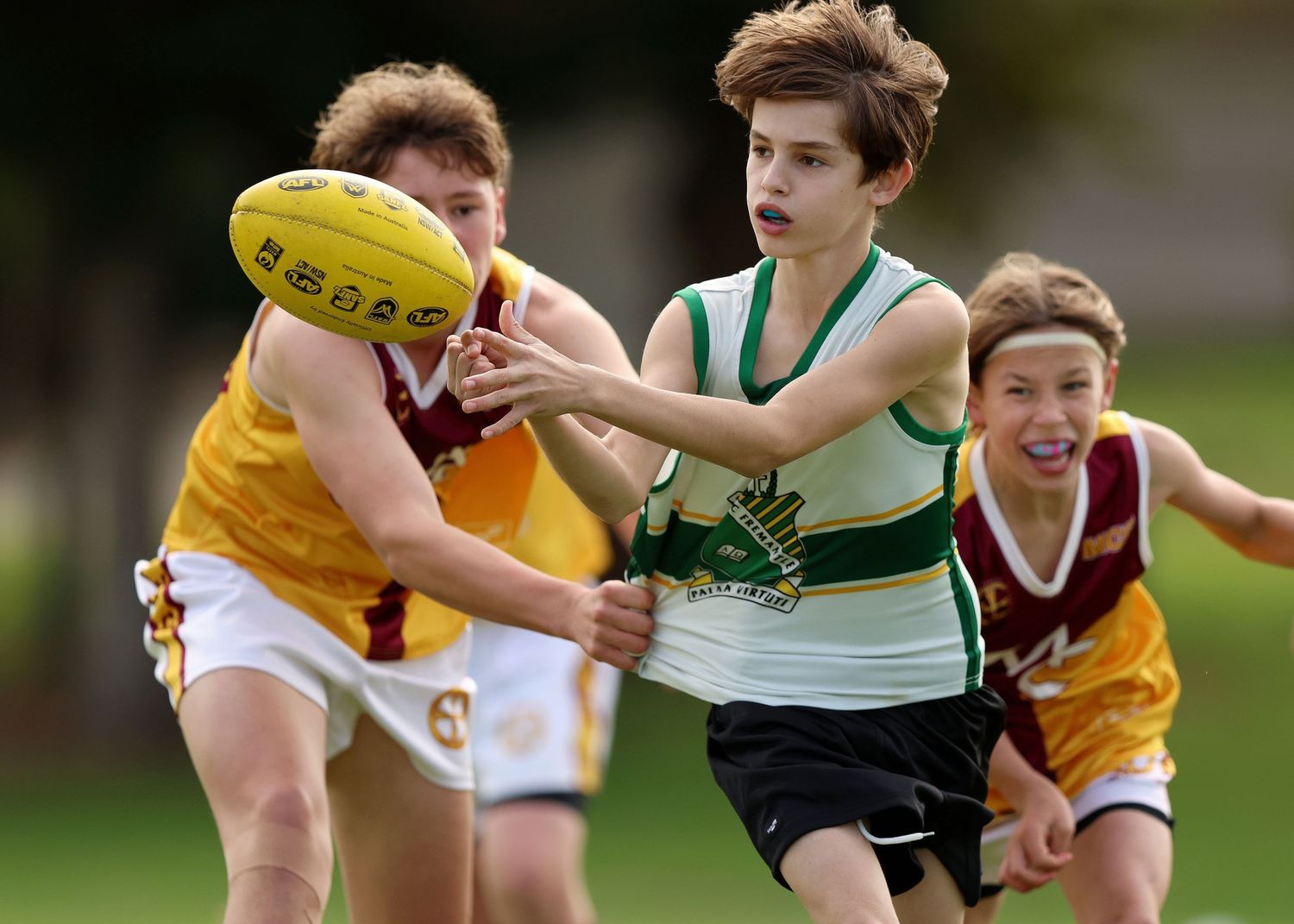 Action shot of youth Australian football players competing for control of the football during a match.