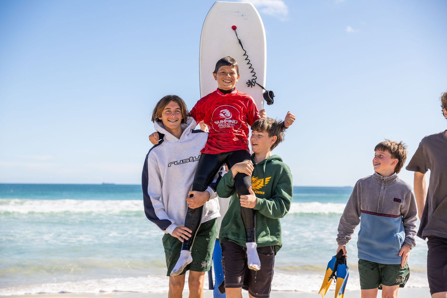 Group of people on a beach with fishing rods engage in outdoor surf fishing activity on a sunny day.
