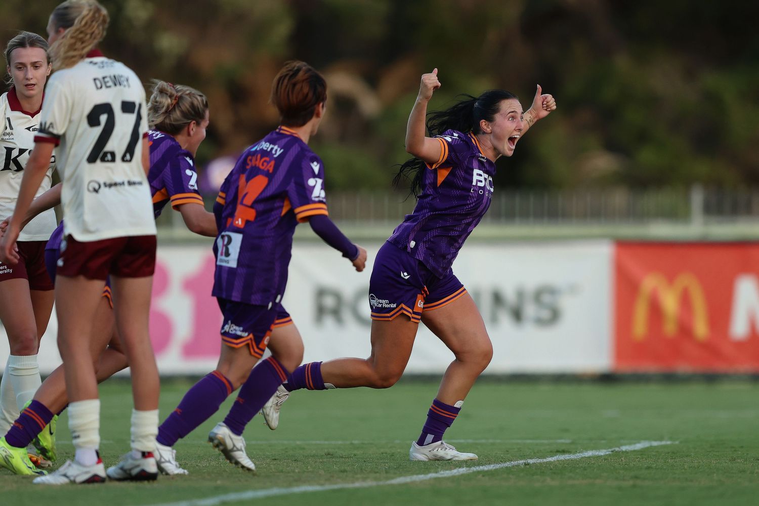 Athletes celebrating goal during sports match with arms raised.