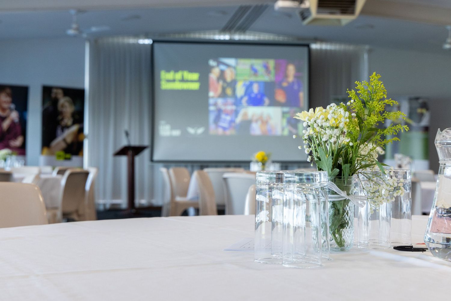 Modern conference room setup with floral centerpiece and projection screen showing presentation.