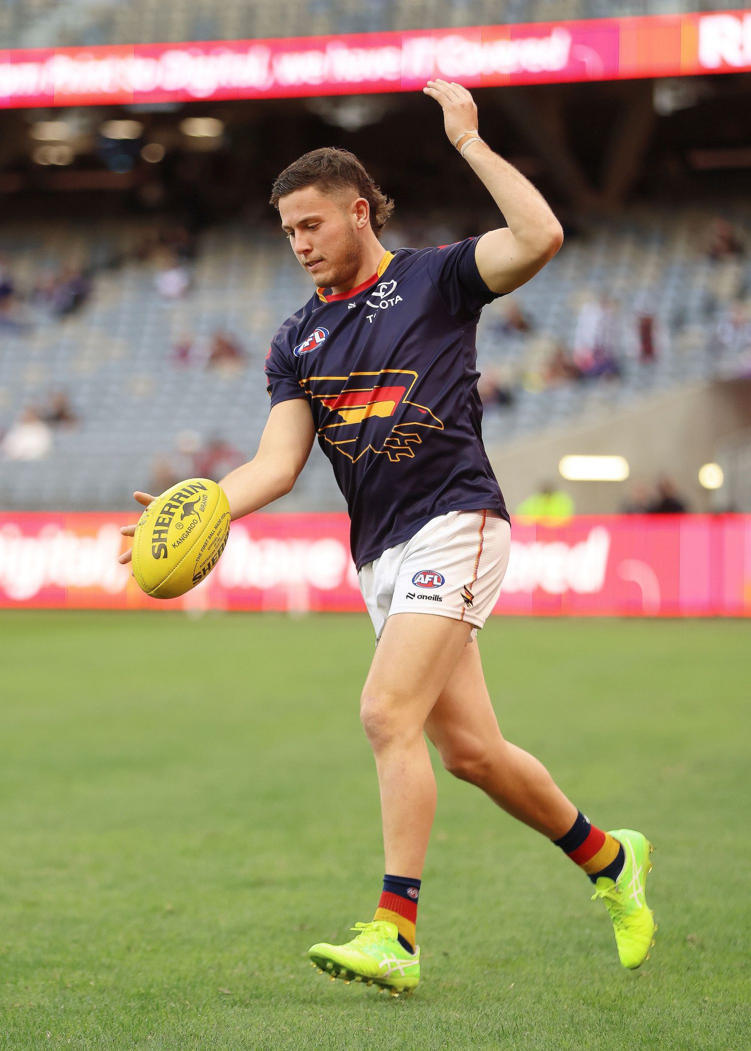 Adelaide Crows player prepares to kick the ball during AFL match.