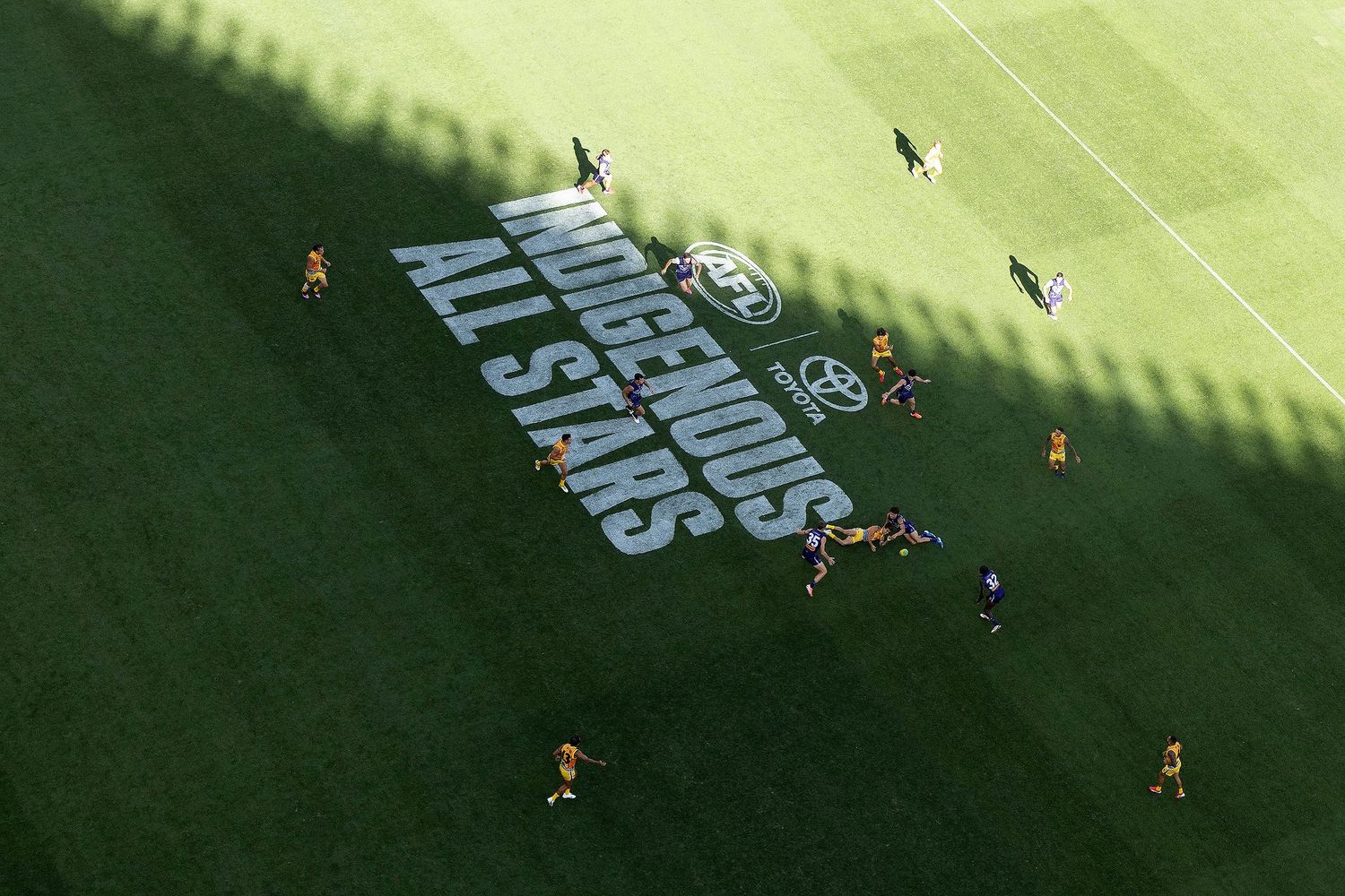 Aerial view of football field with stadium sponsors text graphics displayed on turf.