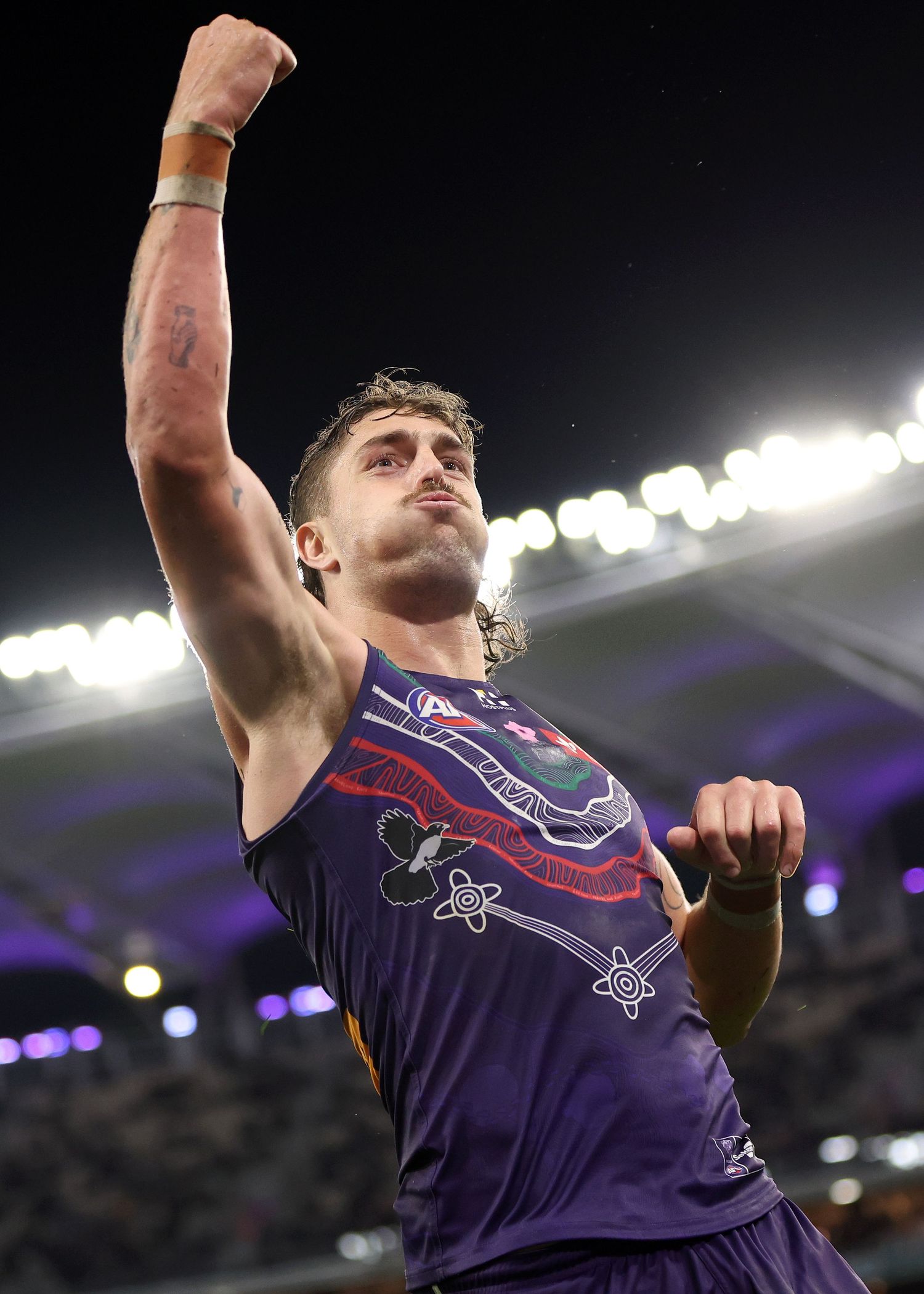 Progressive sequence showing jumper in purple athletic tank top leaping and celebrating in stadium at night.