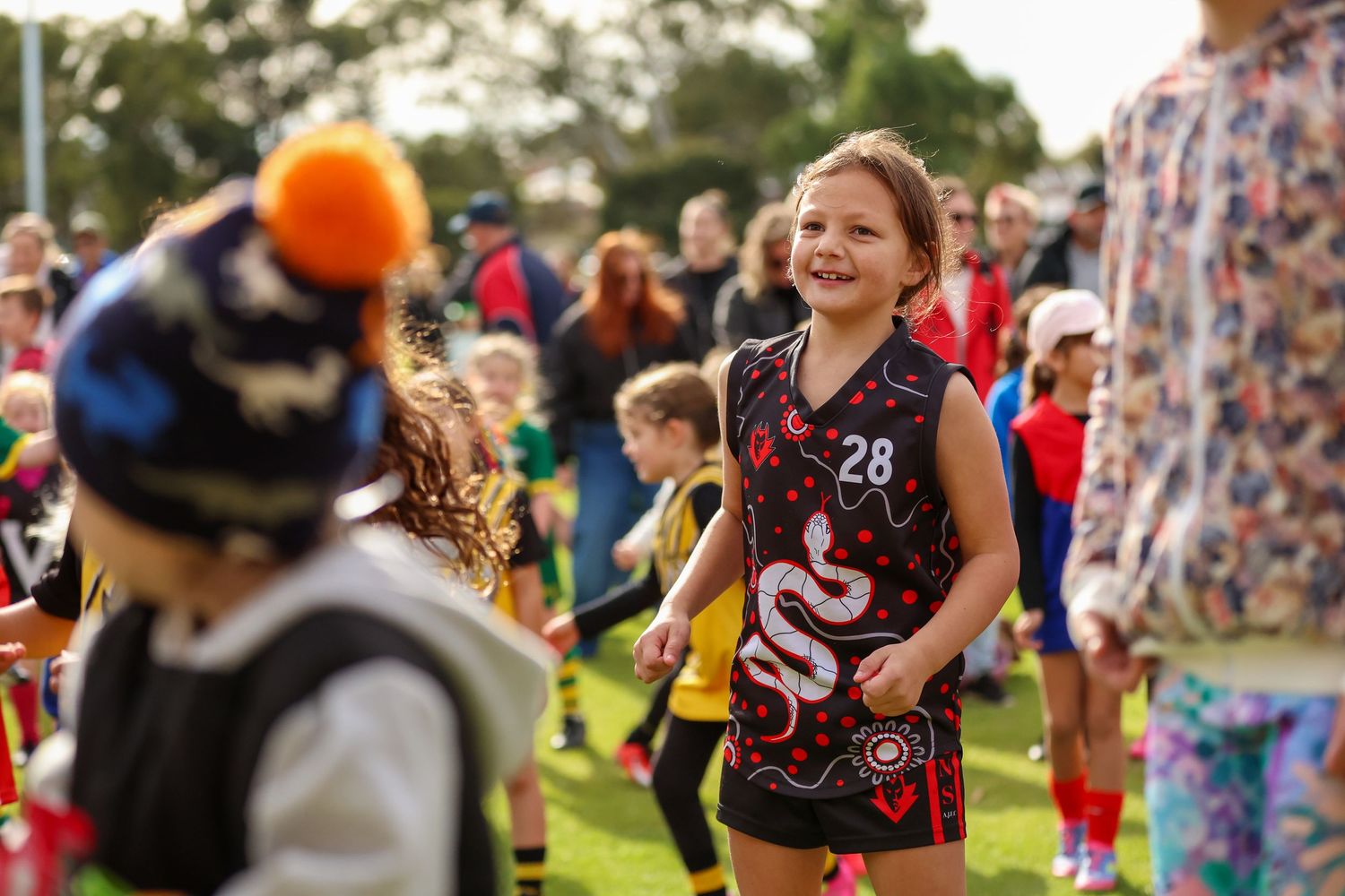 Children play together at an outdoor sports camp while wearing matching uniforms during a summer activity.