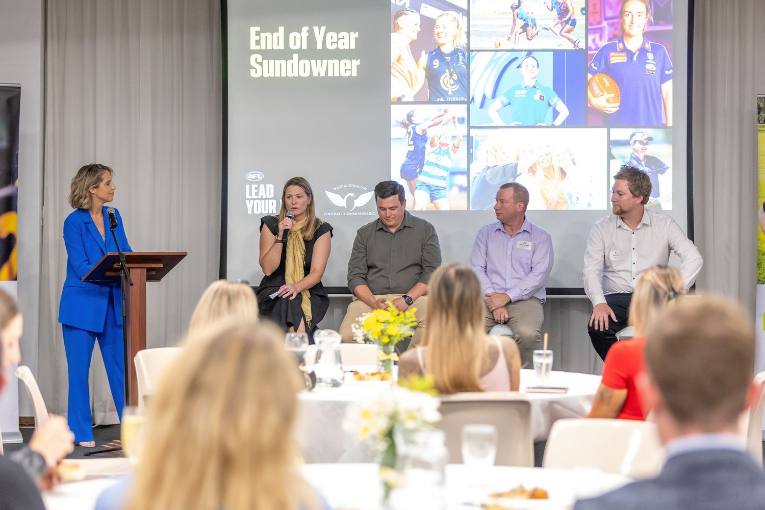 Business presentation with speaker and panel discussion in corporate conference setting.