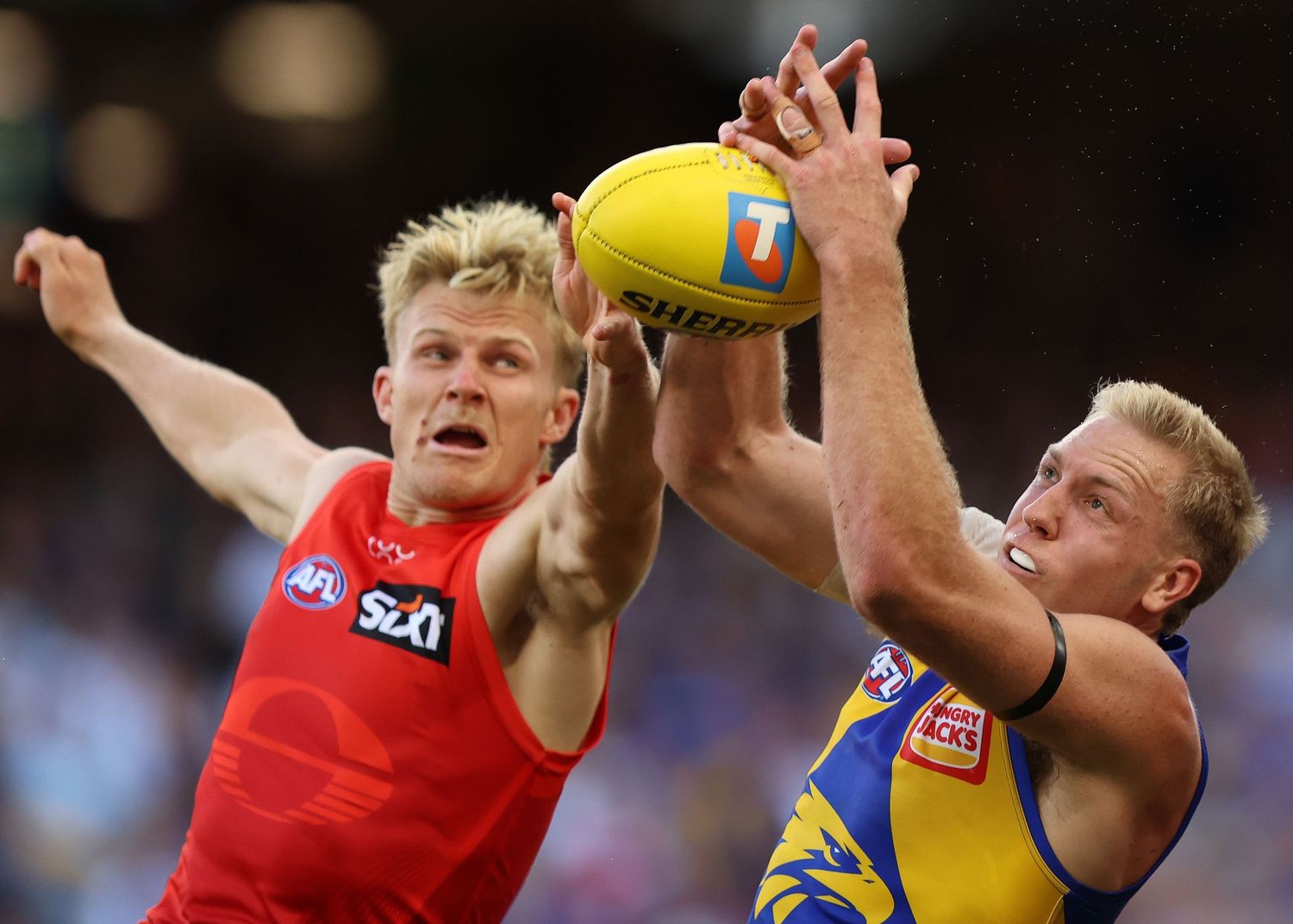Two AFL players leap and compete for the ball during intense match action.