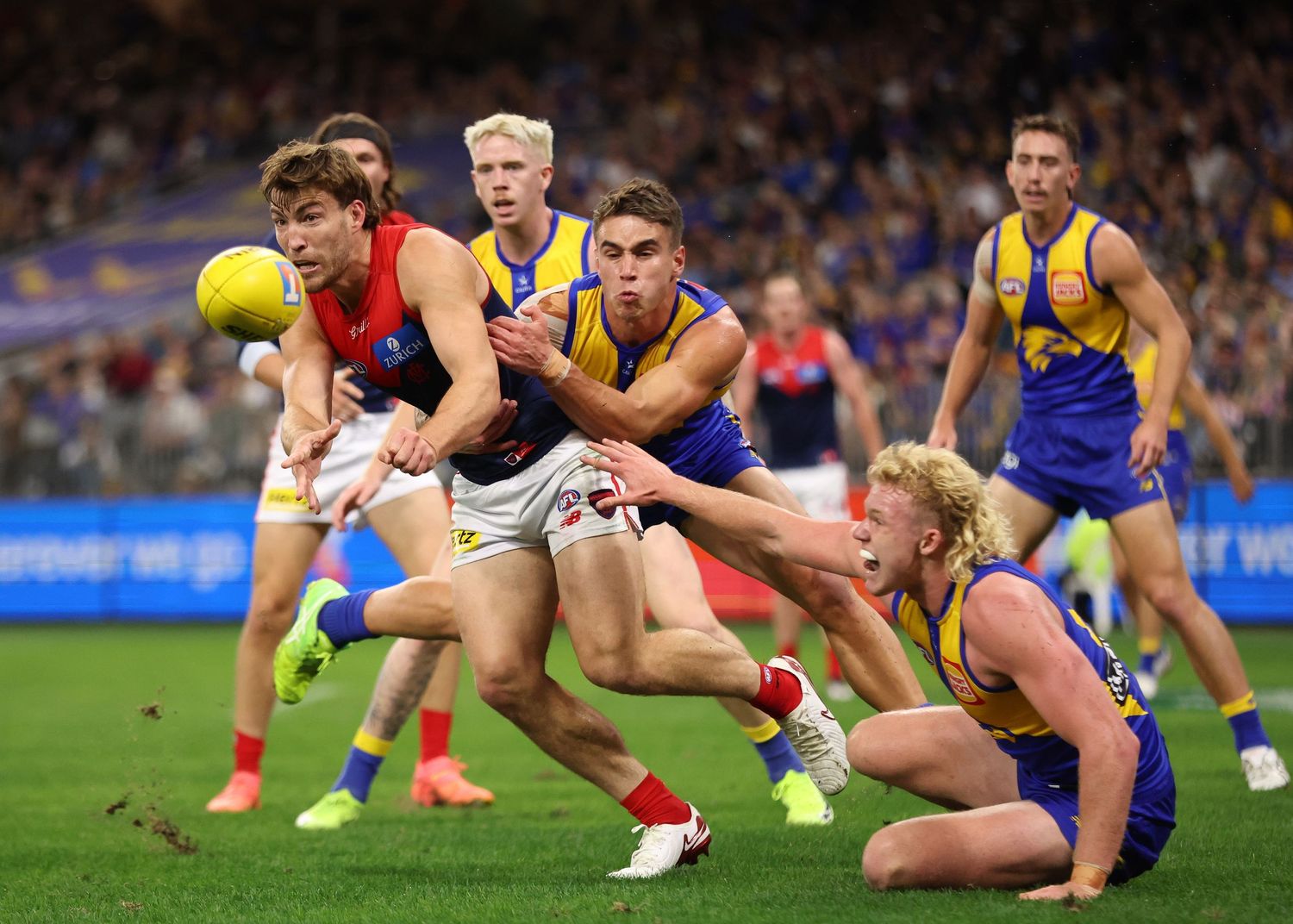 Players from opposing AFL teams scramble for possession of the ball during an intense match.