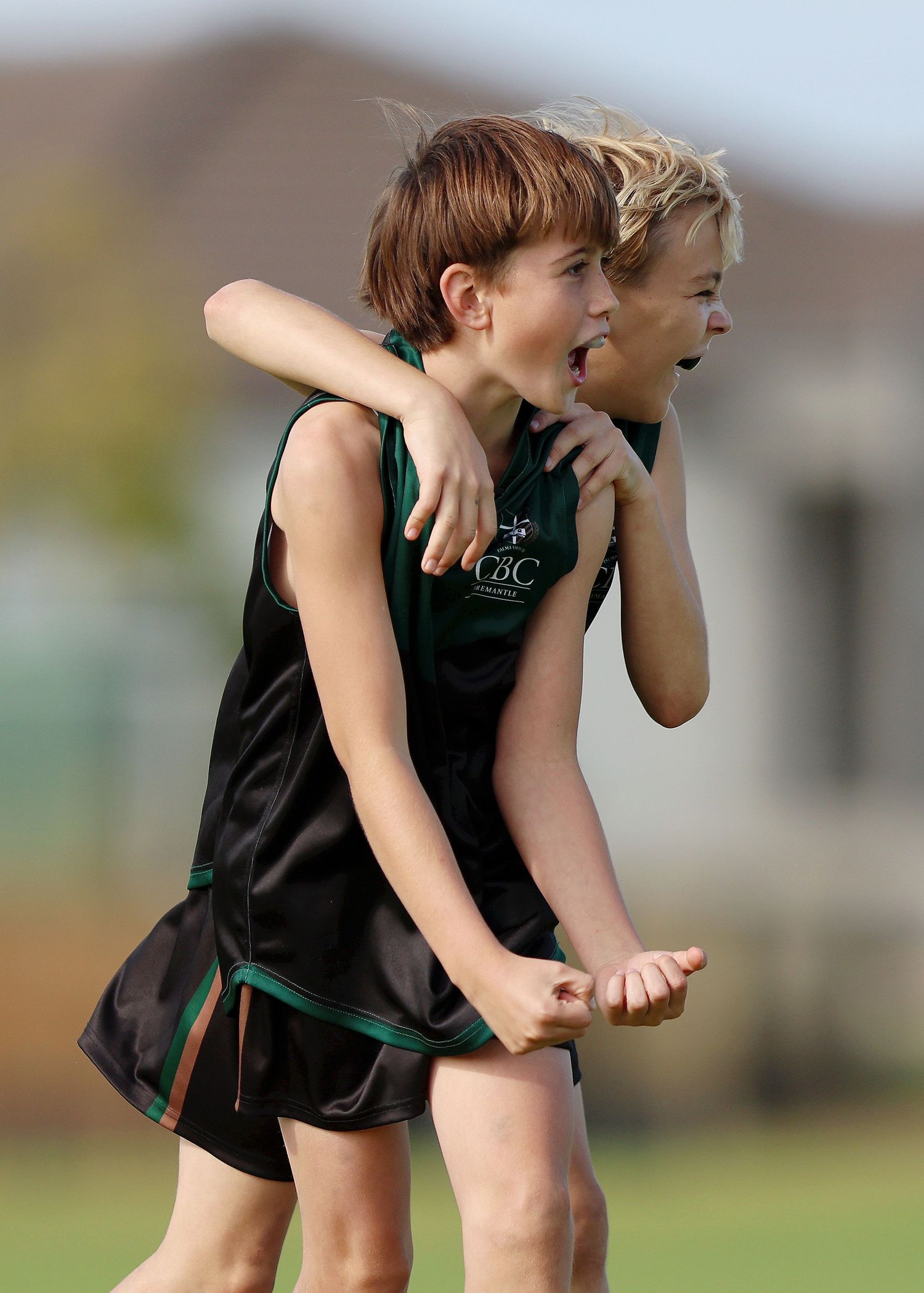 Two athletes wearing black uniforms share an excited reaction while watching an event during a sporting competition.