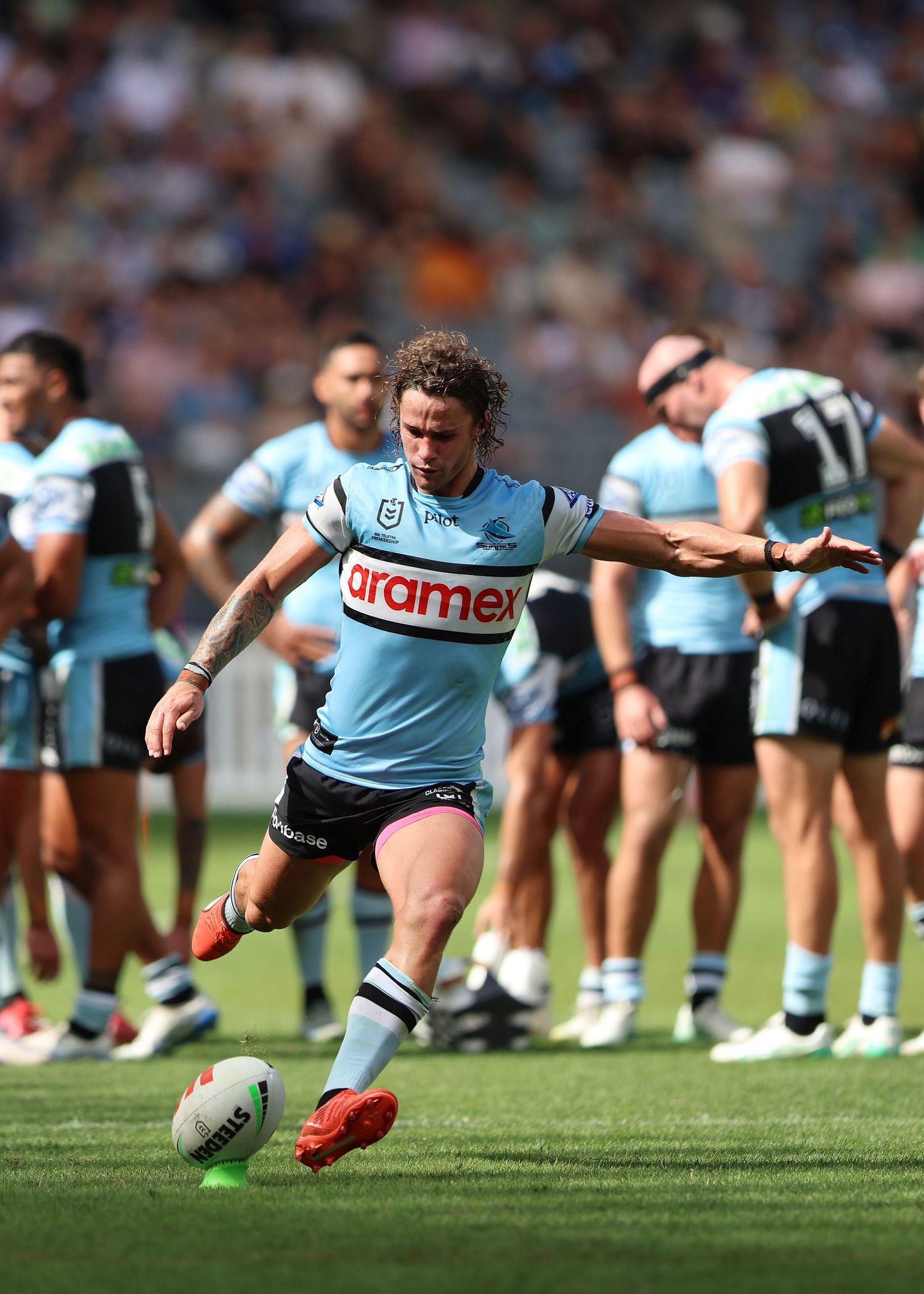 Player in light blue uniform practices kicking during team training session.