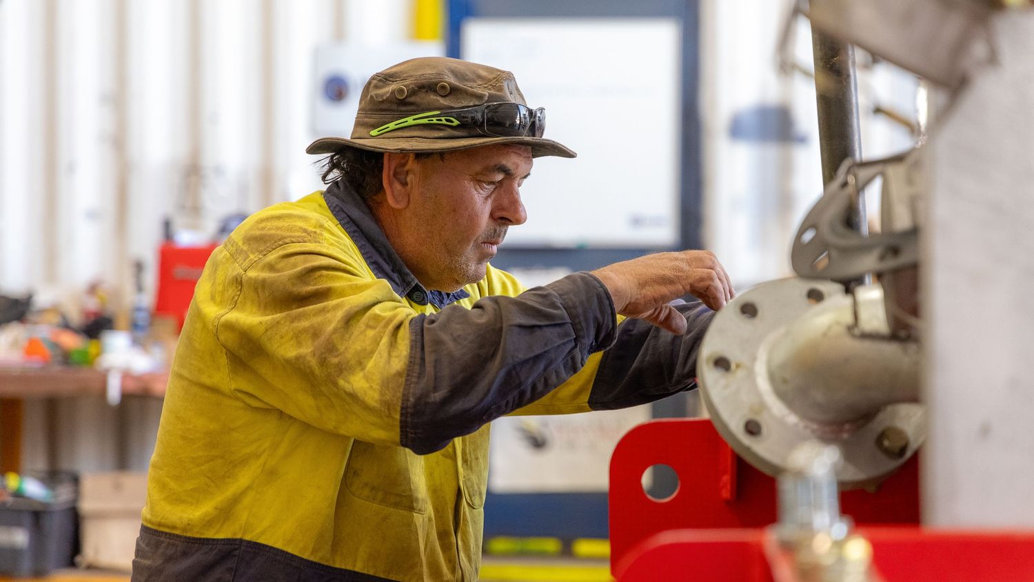 Workers in yellow protective gear perform safety checks at an industrial facility.