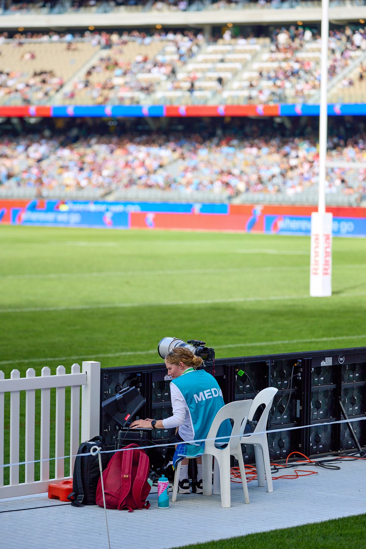 Media photographer working at sideline station during sports match.