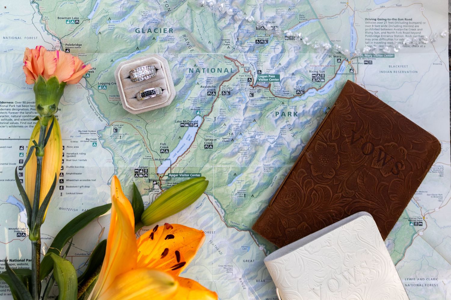 A flat lay of a map, ring box, passport holder, flowers, and a white card, perfect for travel wedding planning.