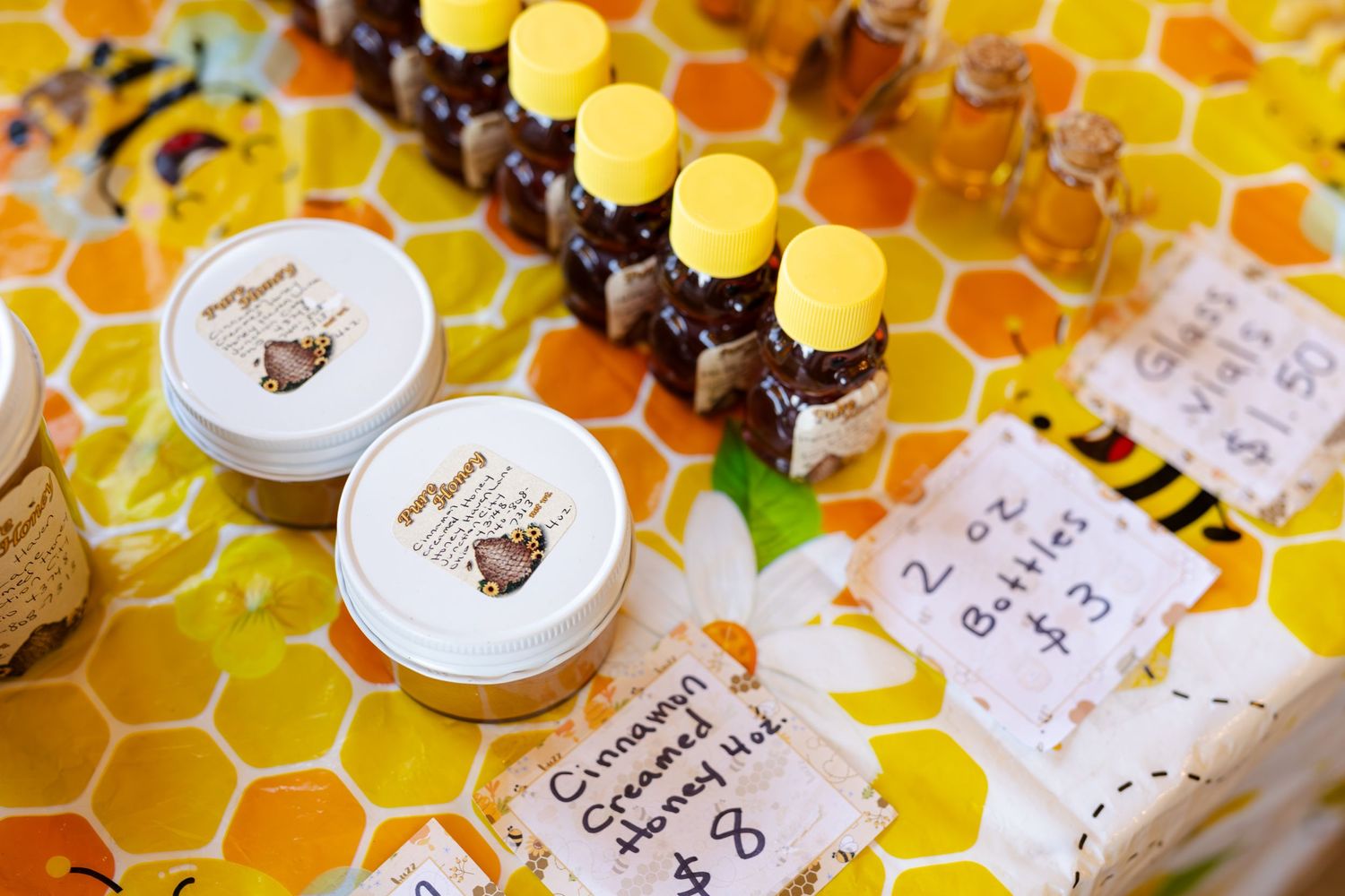 Assorted honey products including creamed honey jars and small bottles at a market stall.