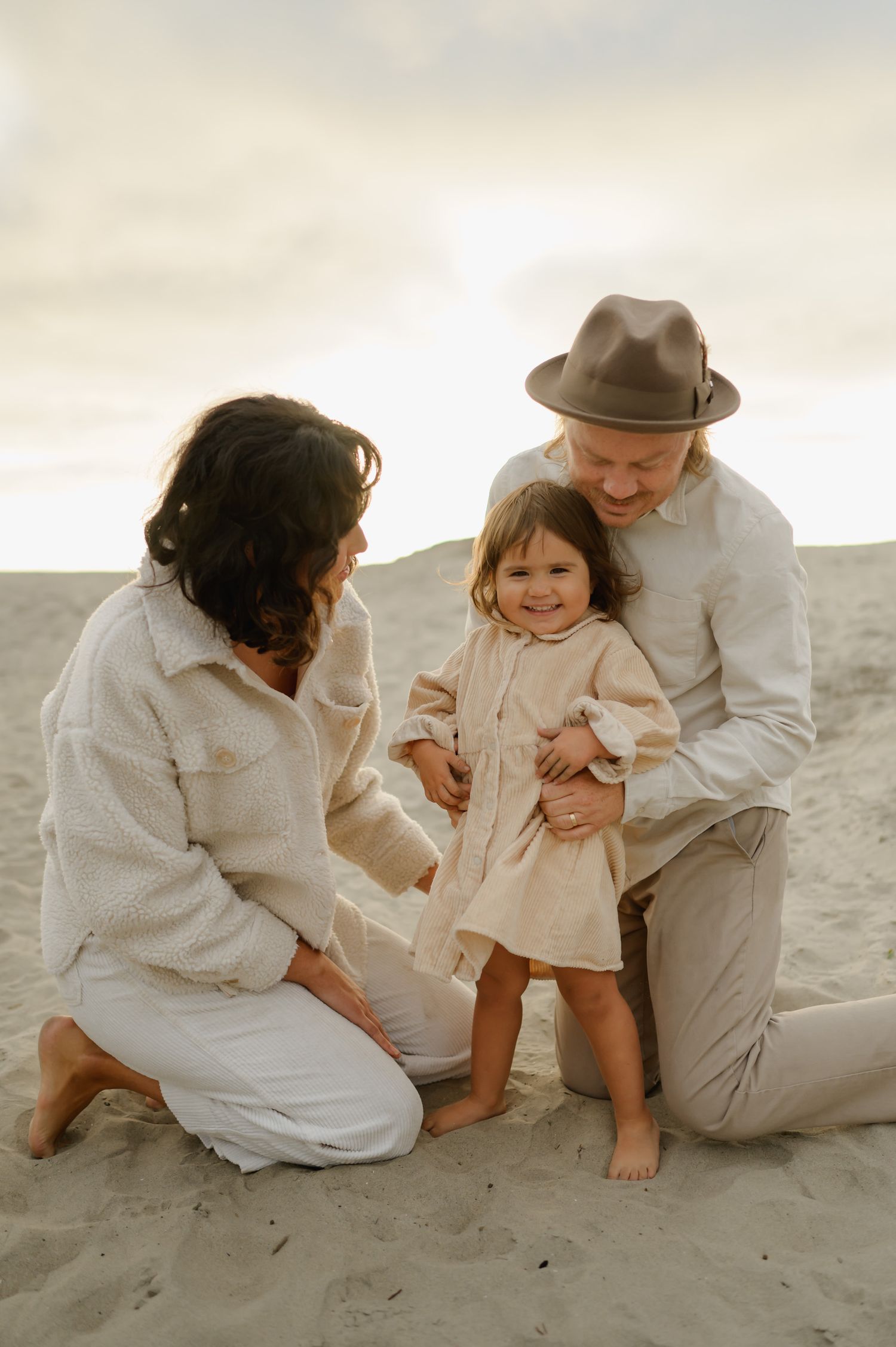 family cuddling their daughter during their family beach photoshoot by Ventura county photographer