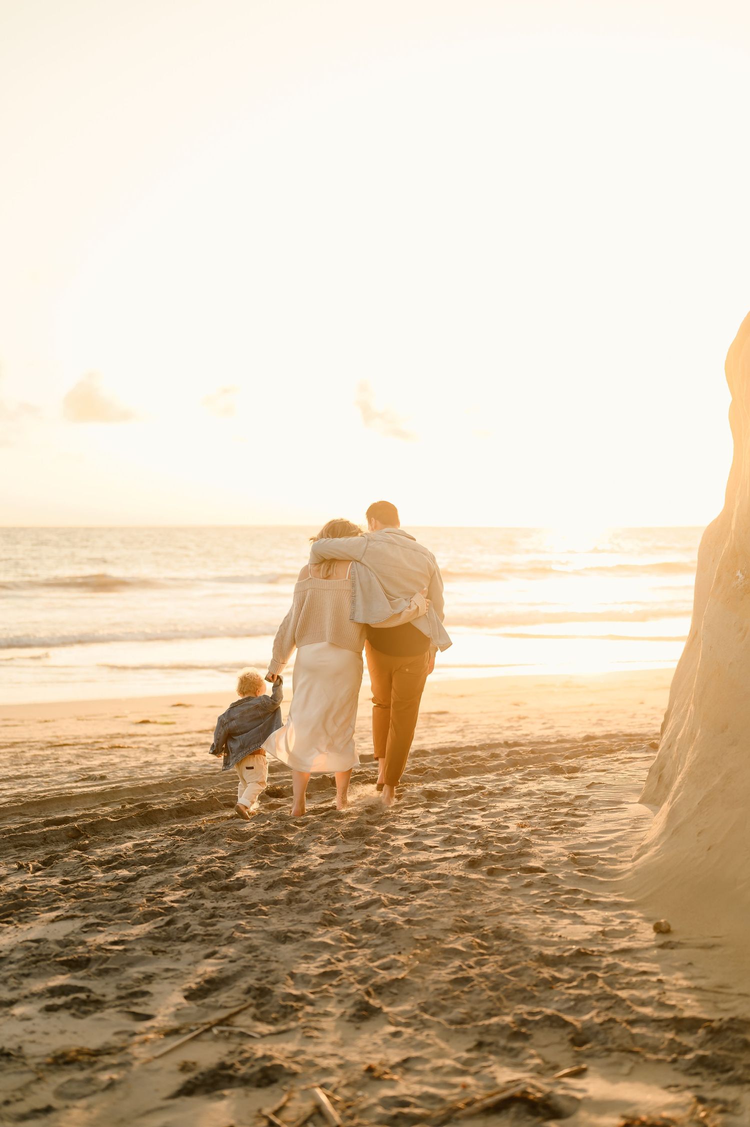 A family walking on Carpinteria beach at sunset during family photoshoot by Ventura family photographer