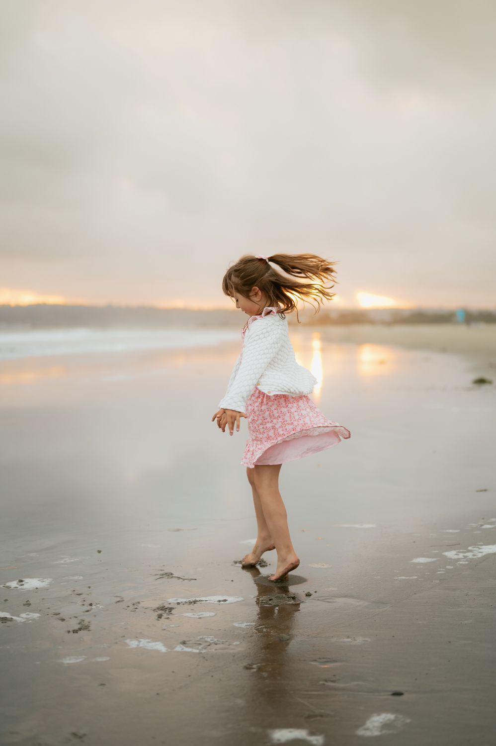 little girl playing on glassy sand during family photoshoot by Ventura County family photographer