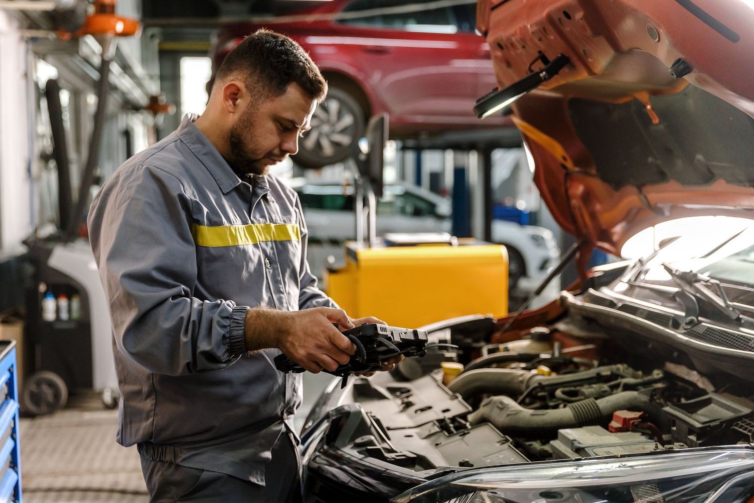 Auto mechanic inspecting car engine components in a professional repair garage.