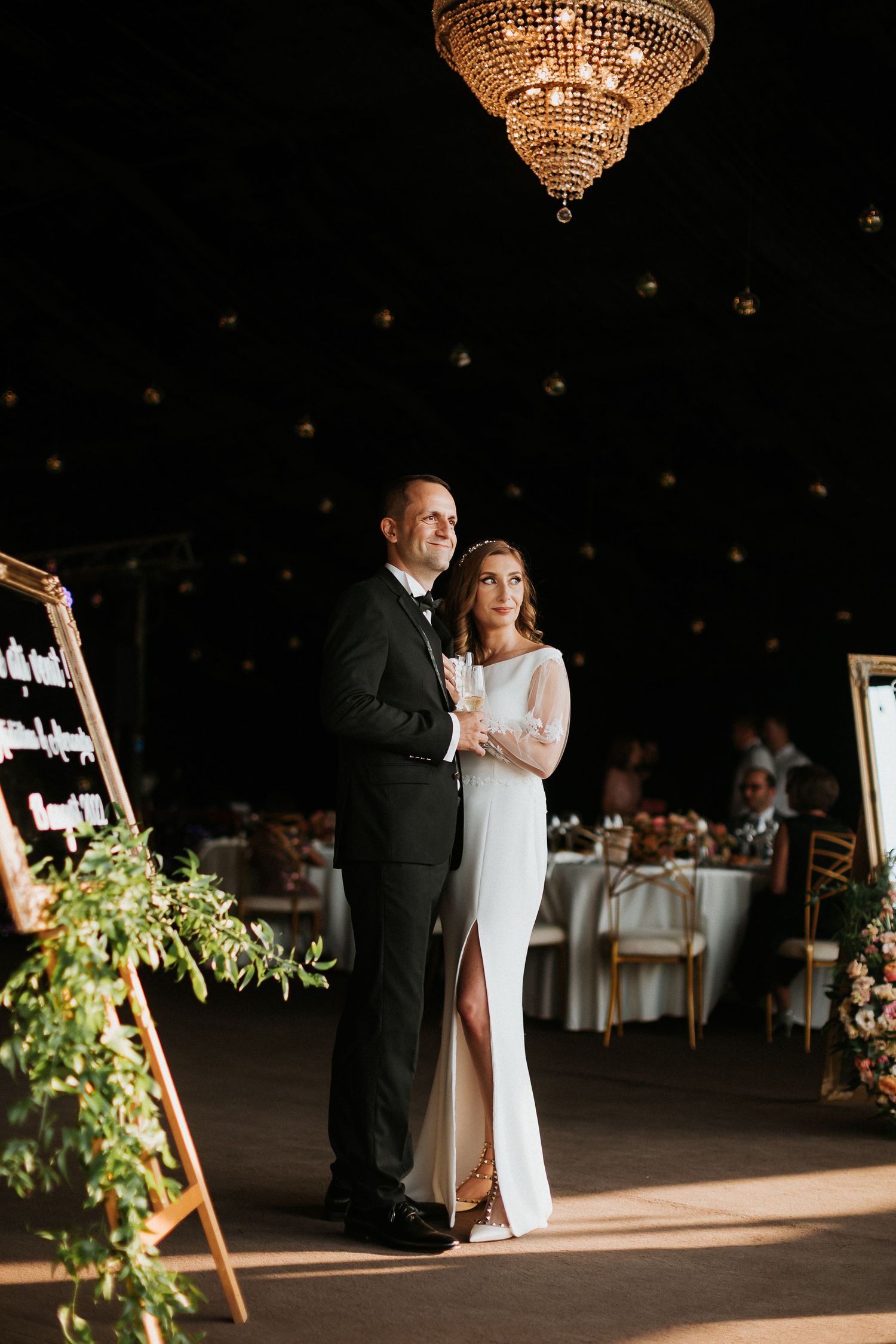 Bride and groom share a romantic moment under a crystal chandelier at their elegant wedding reception.