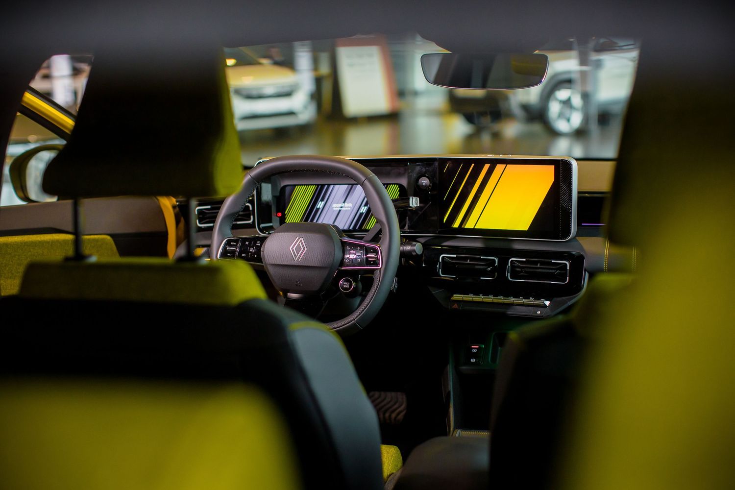 Modern car interior with yellow accents, digital dashboard, large touchscreen display, and sleek steering wheel in a showroom.