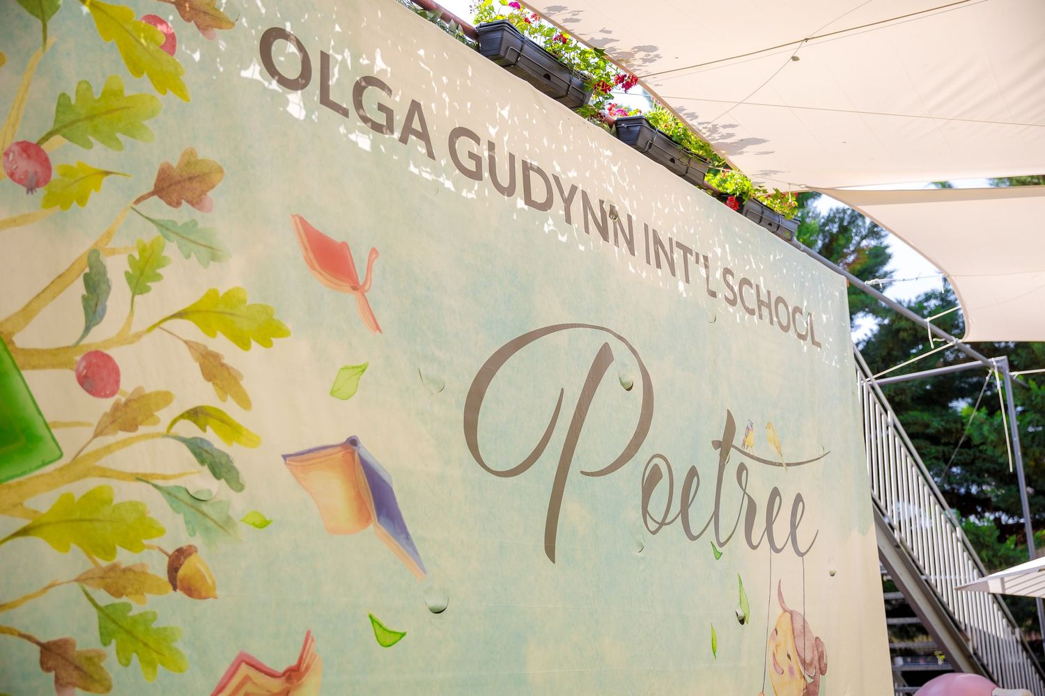 Olga Gudynn International School Poetree event banner with colorful autumn leaves and book illustrations.