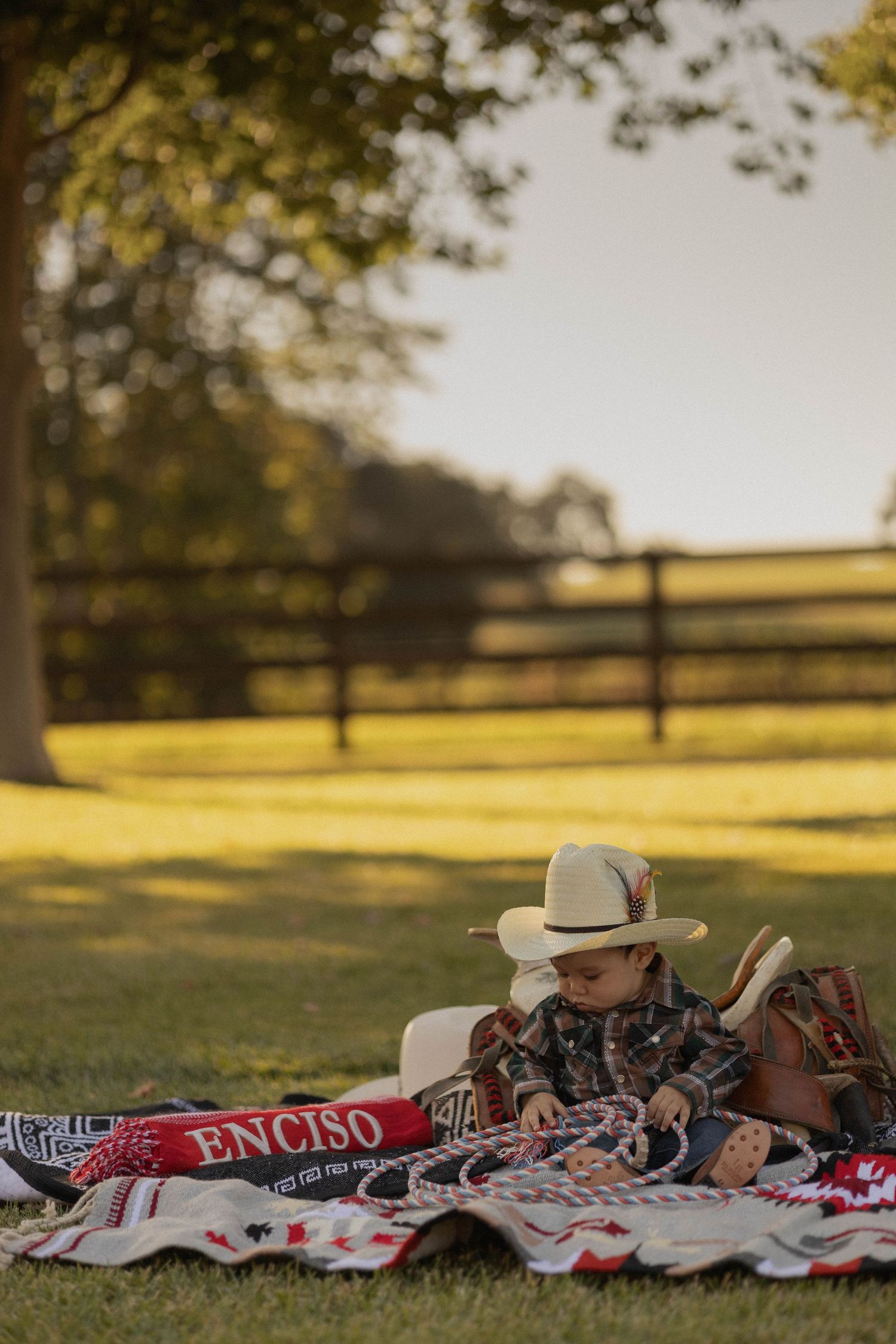 picture depicting child sitting in grass during golden hour with a cowboy theme decorations