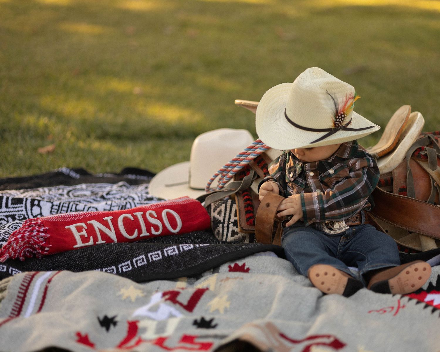 picture depicting child sitting in grass during golden hour with a cowboy theme decorations