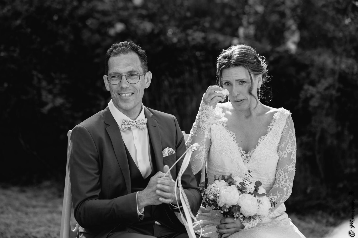 Photographie noire et blanc d'un couple de mariés, pendant leur cérémonie laïque, l'épouse est émue et a la larme à l'oeil.