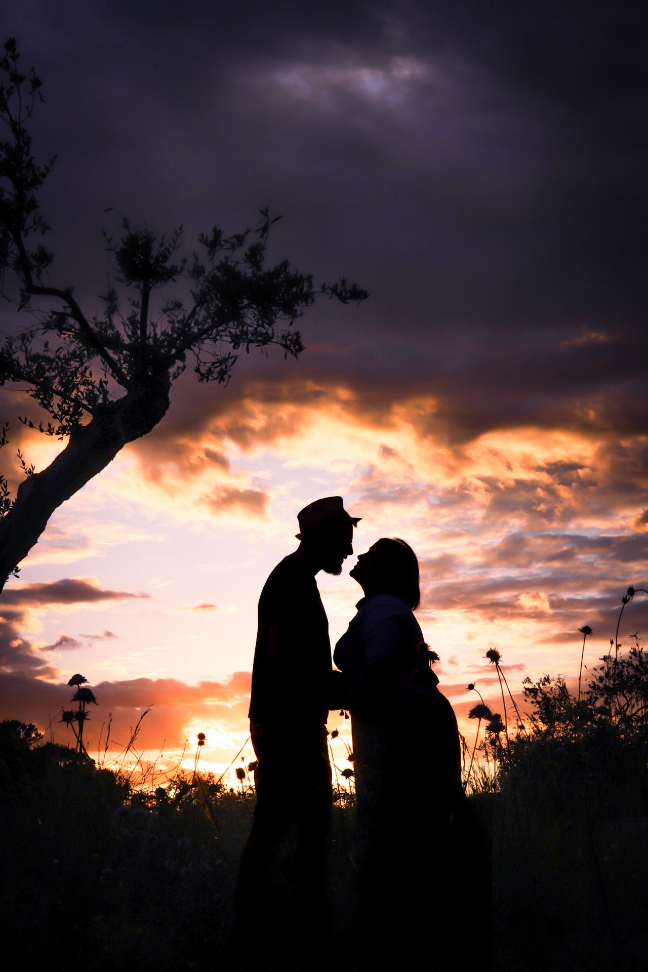 Silhouette of a couple sharing a romantic moment under a dramatic colorful sunset sky.