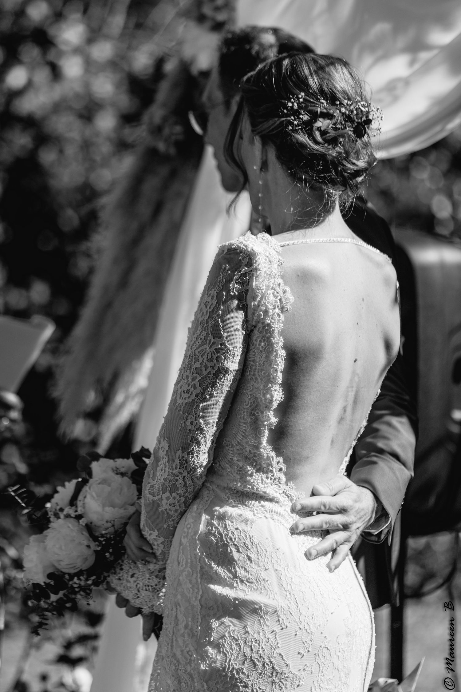 Black and white close-up of bride in backless lace gown with elegant updo hairstyle.