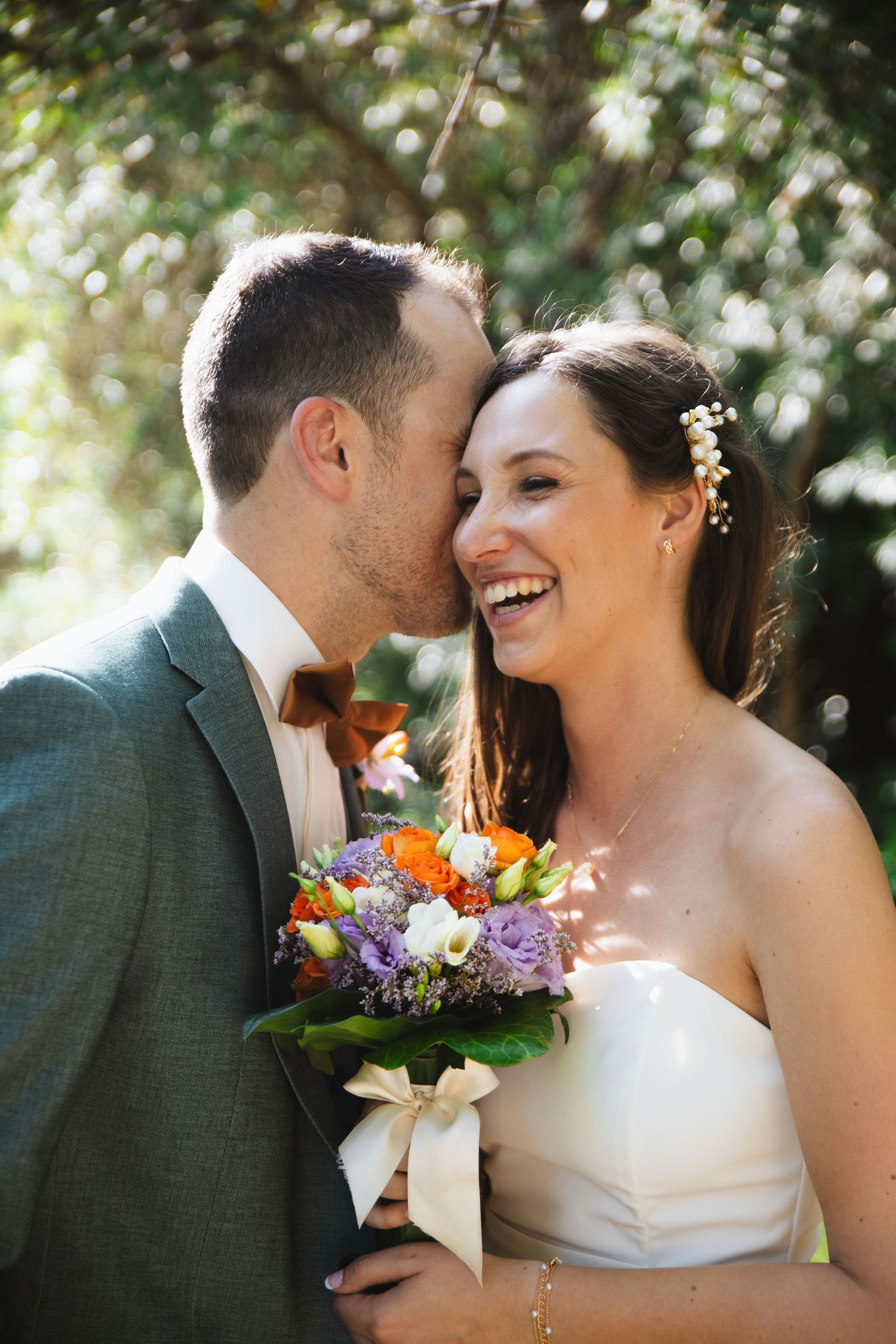Couple de mariés, le mari dit un petit mot à l'oreille de sa femme, et elle rit. Photographe mariage Var et Provence