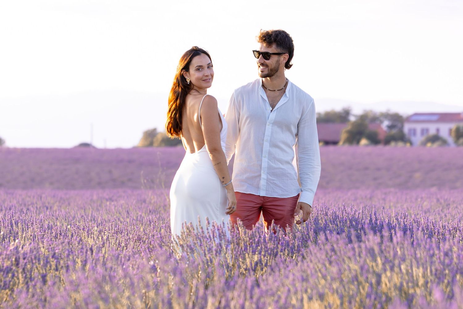 Couple holding hands in a stunning purple lavender field at golden hour.