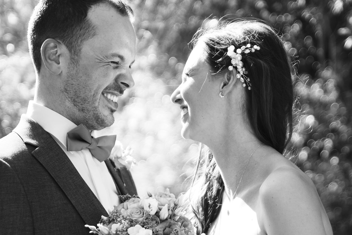Black and white close-up of laughing bride and groom sharing a joyful moment together.