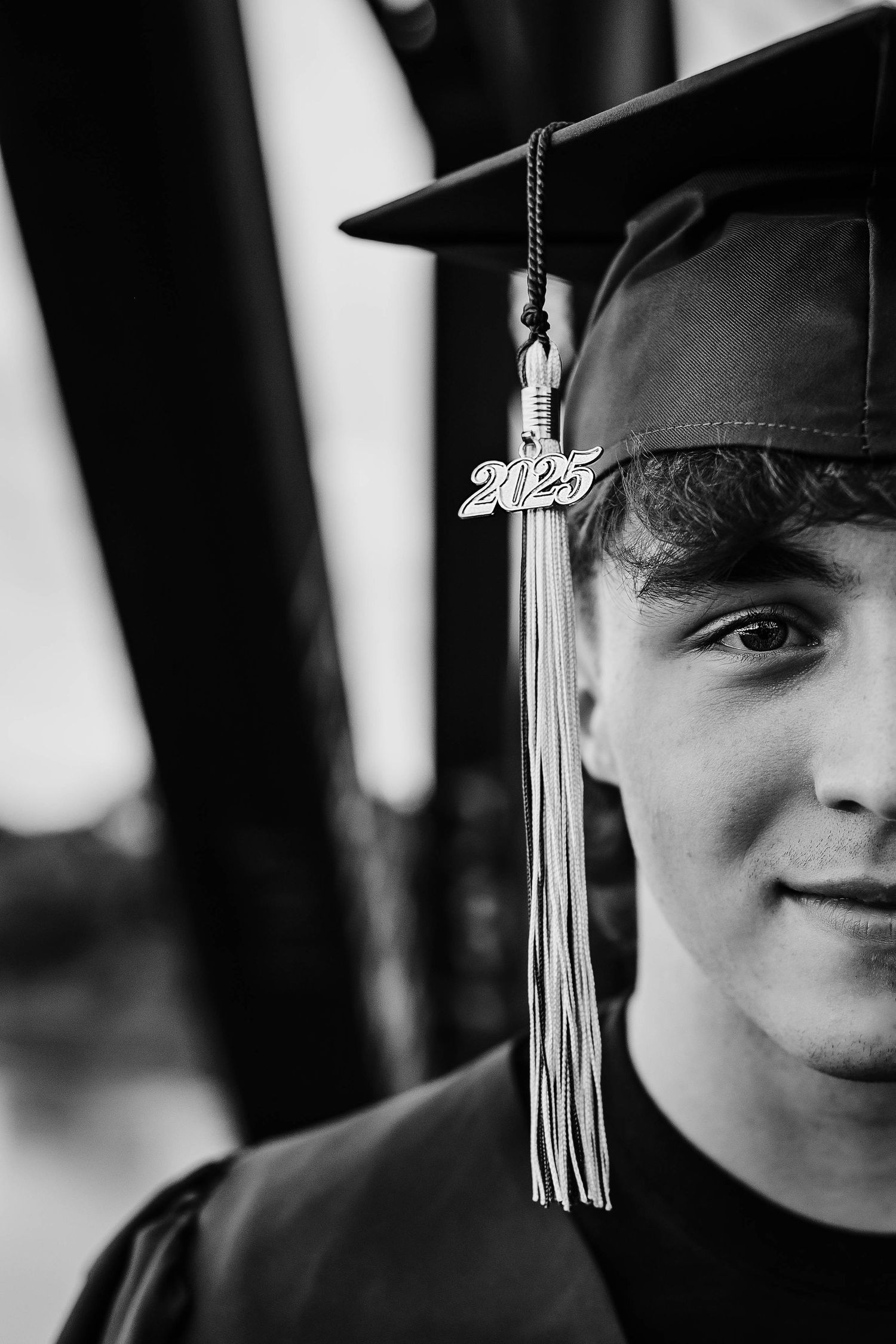 Black and white close-up portrait of young man in 2025 graduation cap.