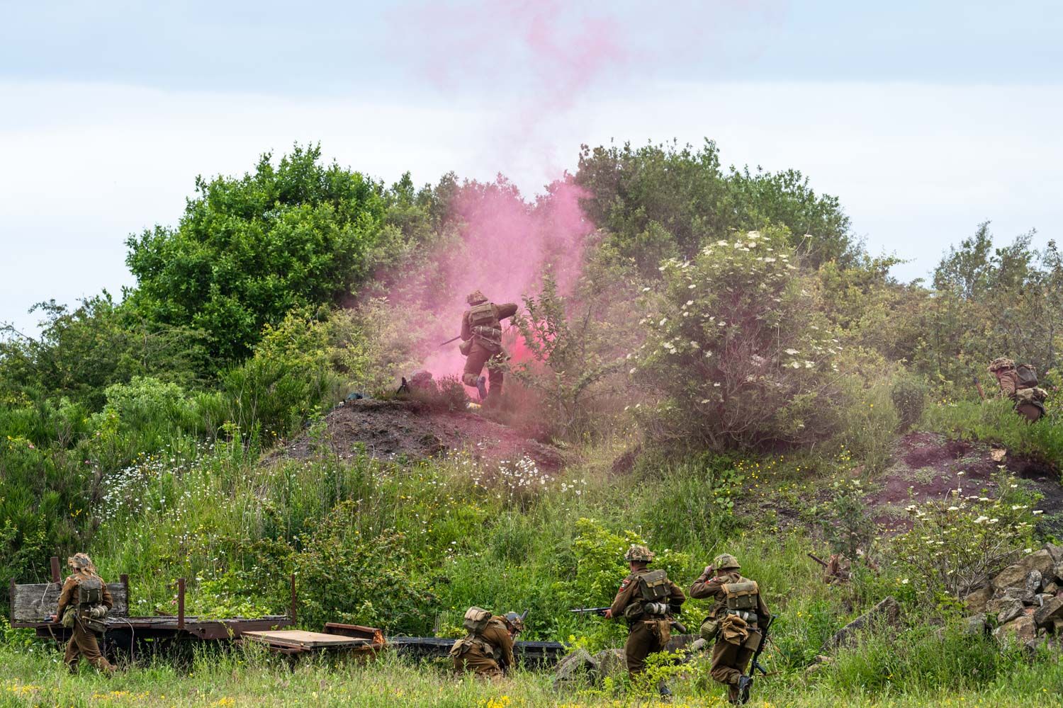 Reenactment of soldiers storming a hillside and releasing red smoke.