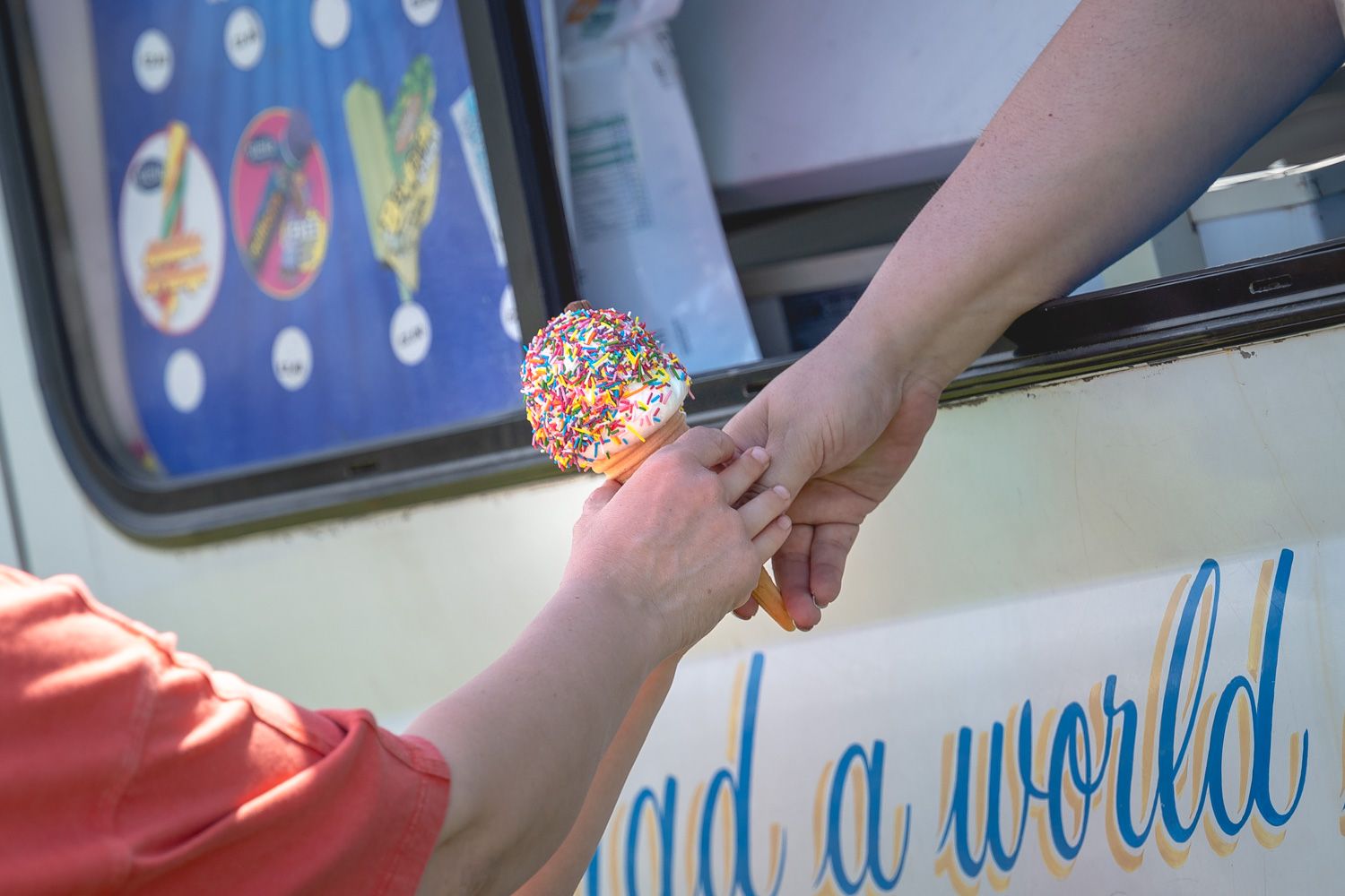 Close up shot of the ice cream van passing an ice cream to a child.